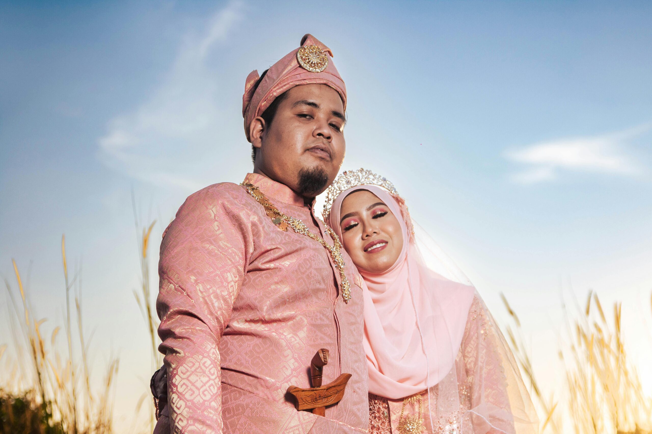 Elegant portrait of a Malaysian couple in traditional wedding attire, captured in a serene outdoor setting.