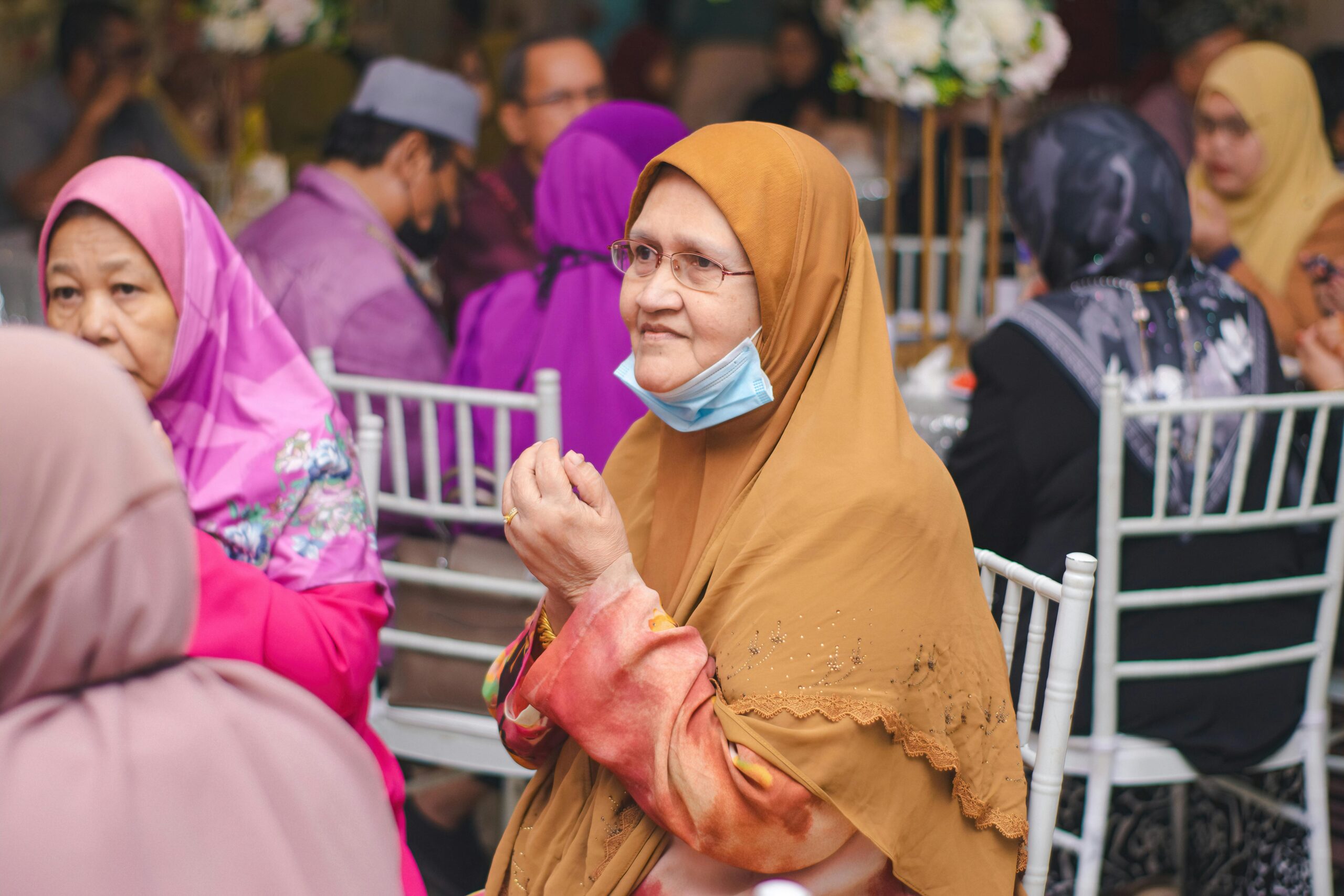 Group of senior women wearing traditional hijabs at an indoor event in Kuala Lumpur, Malaysia.
