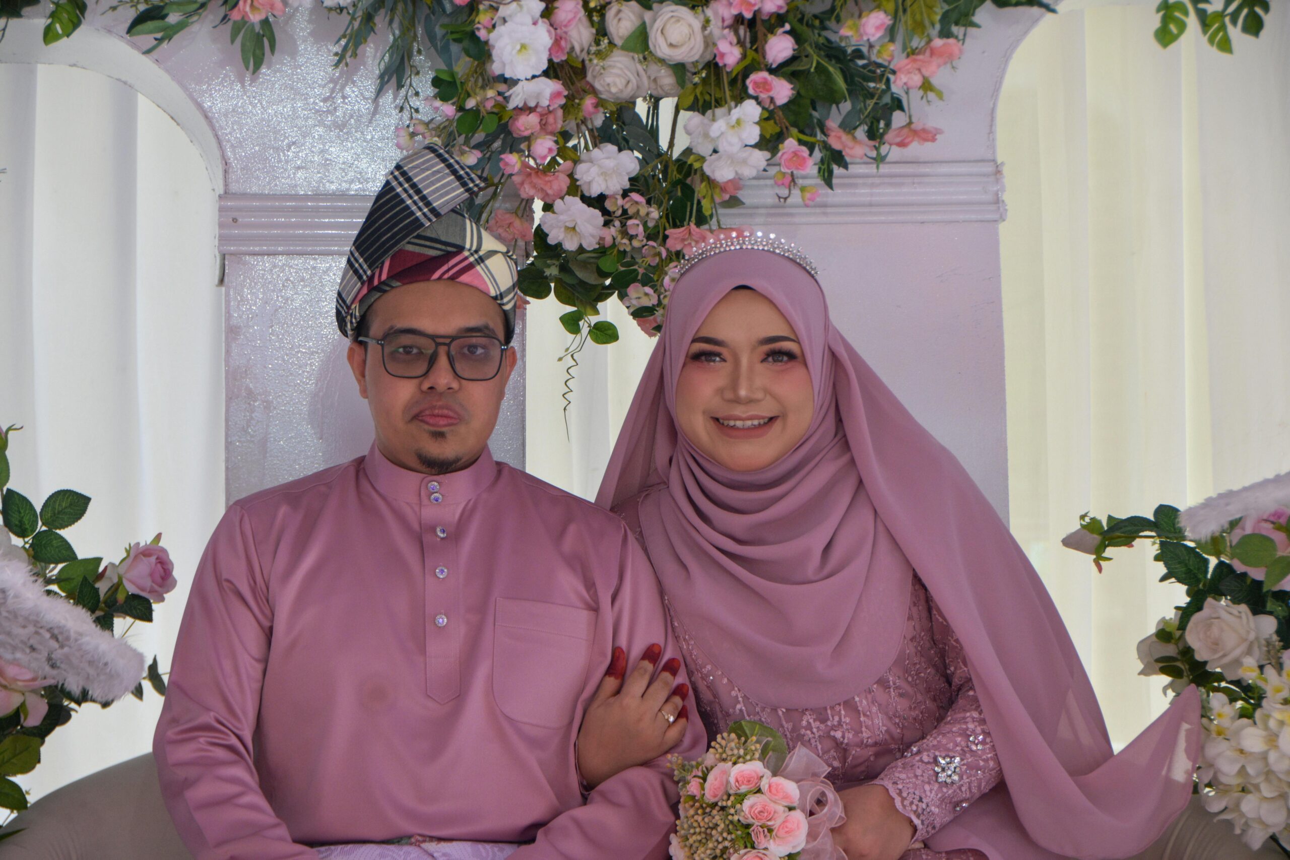 A joyful couple in traditional wear celebrates their marriage with floral decorations.
